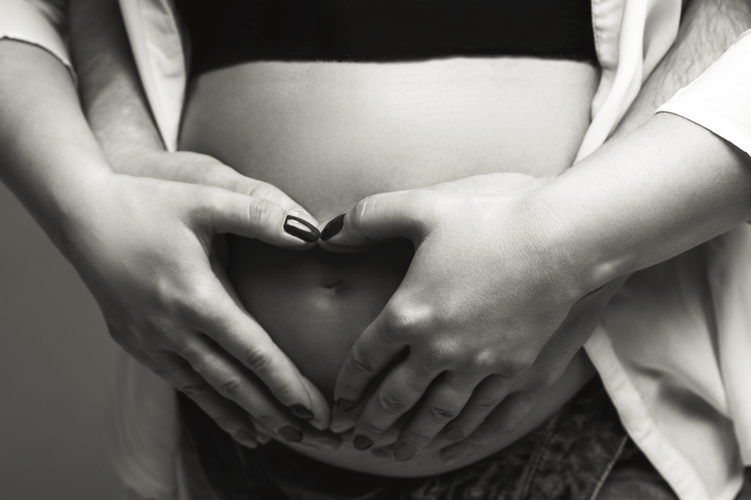 Men’s and women’s hands on a pregnant belly